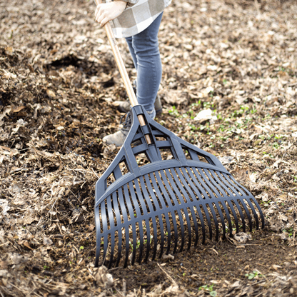 A person using an Extra-Wide Leaf Rake with a handle made from FSC® certified ash wood to collect leaves from the ground.