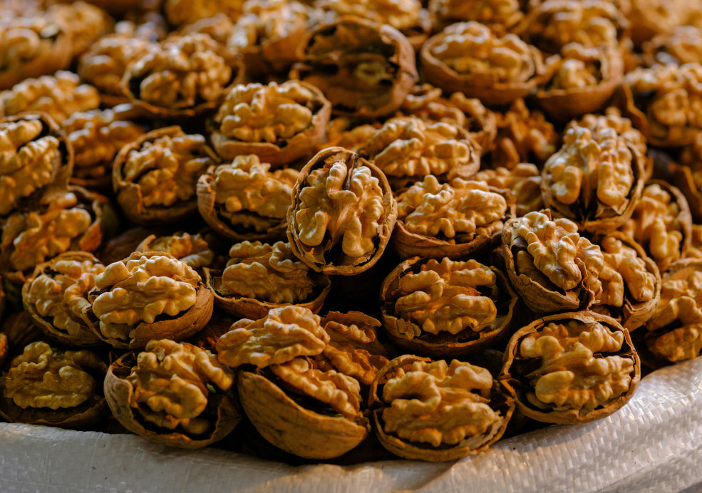 A pile of open walnut shells filled with walnuts.